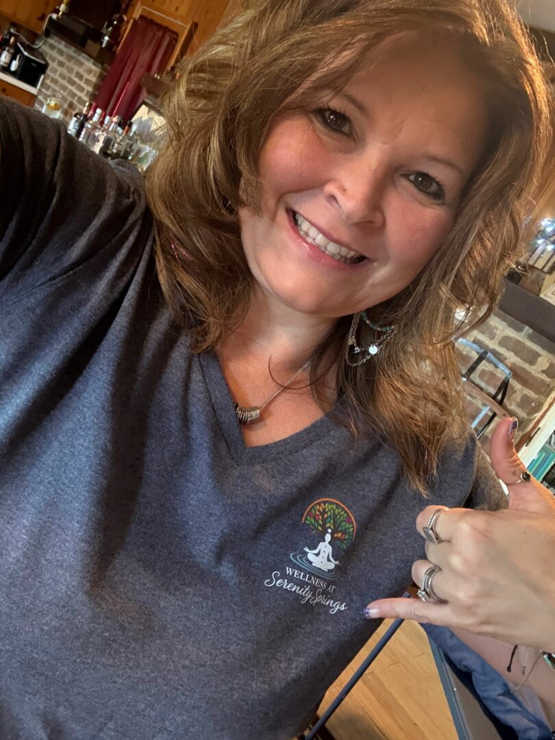 Woman smiling and making a shaka sign with her hand in a bar or restaurant setting.