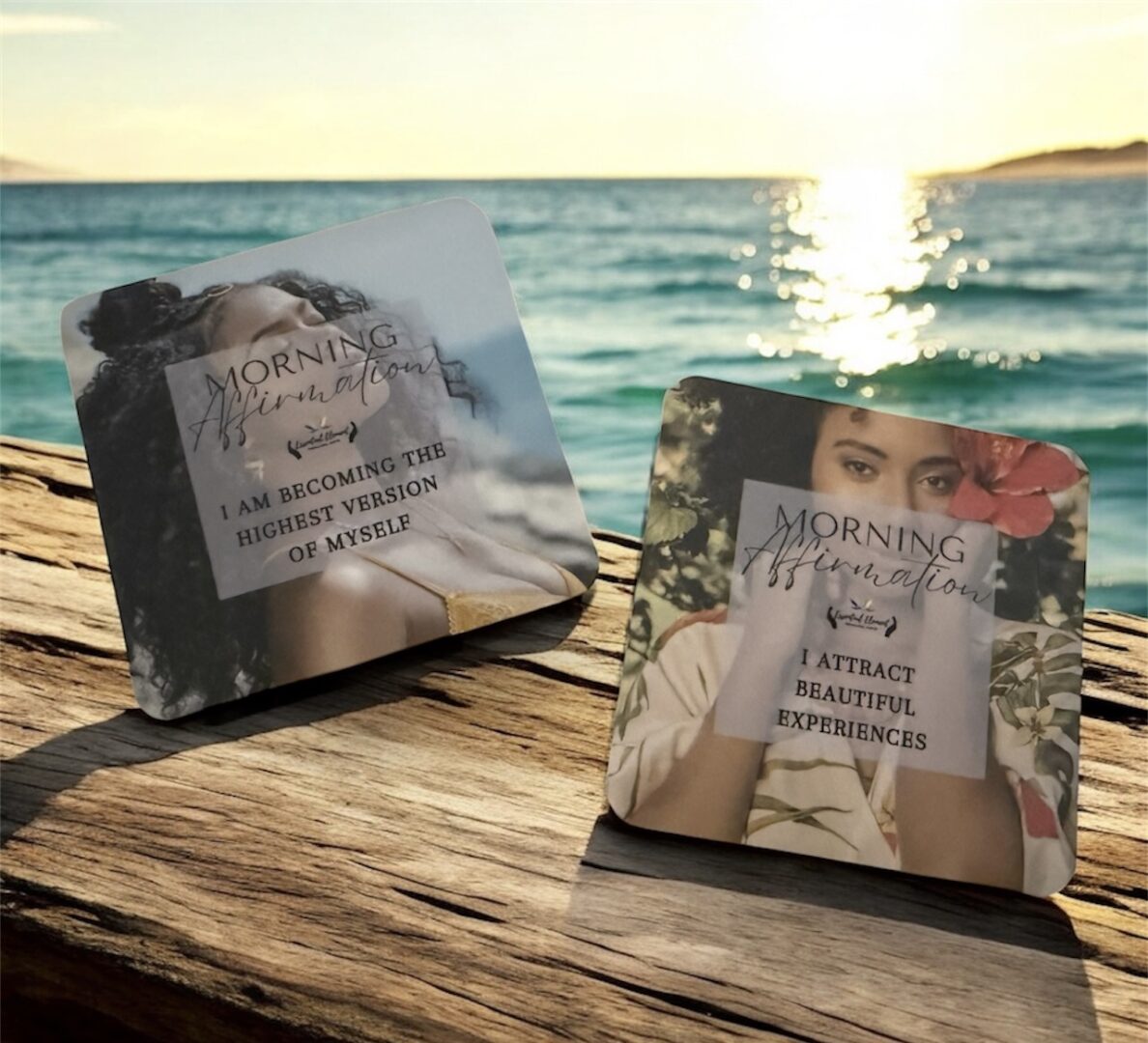 Two square cards with motivational quotes on a wooden surface near water and sunset.