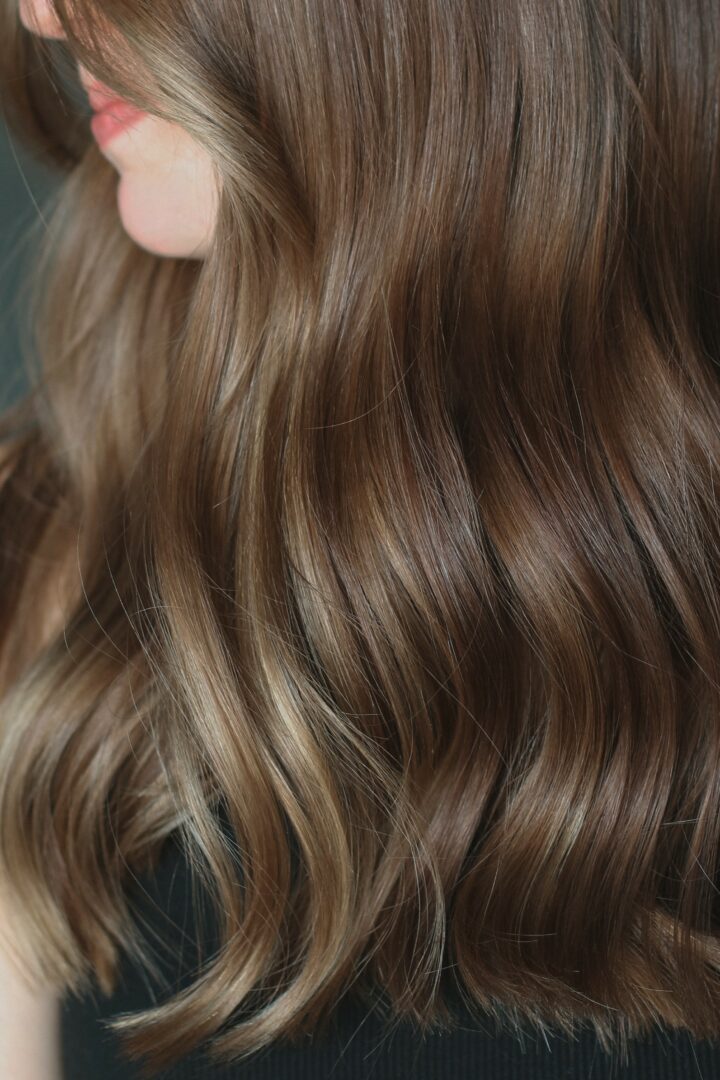 Close-up of a person's face with long, wavy brown hair covering part of their face.