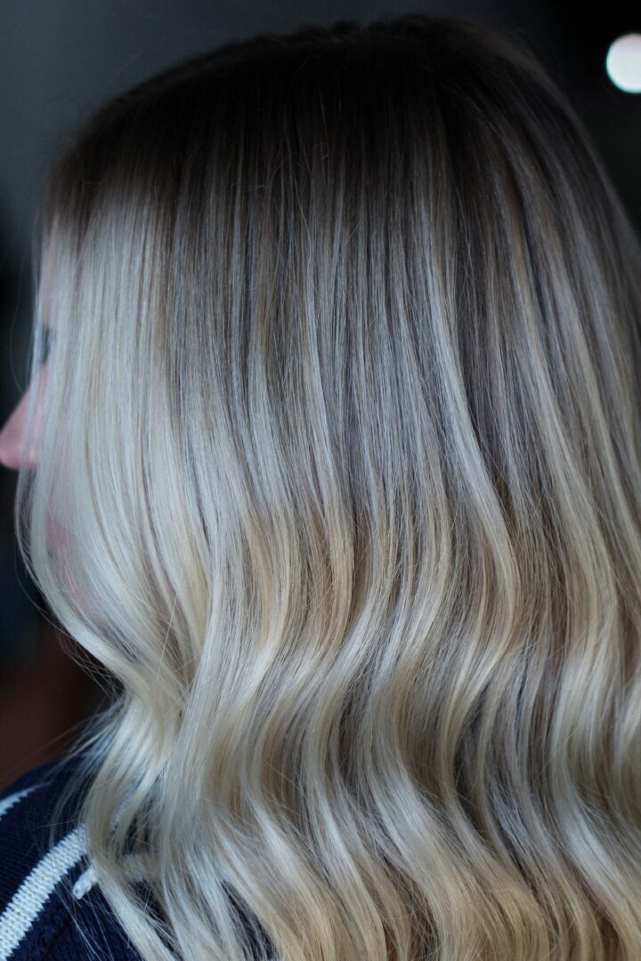 Side view of a person's wavy, ombre hair transitioning from dark to light blonde.