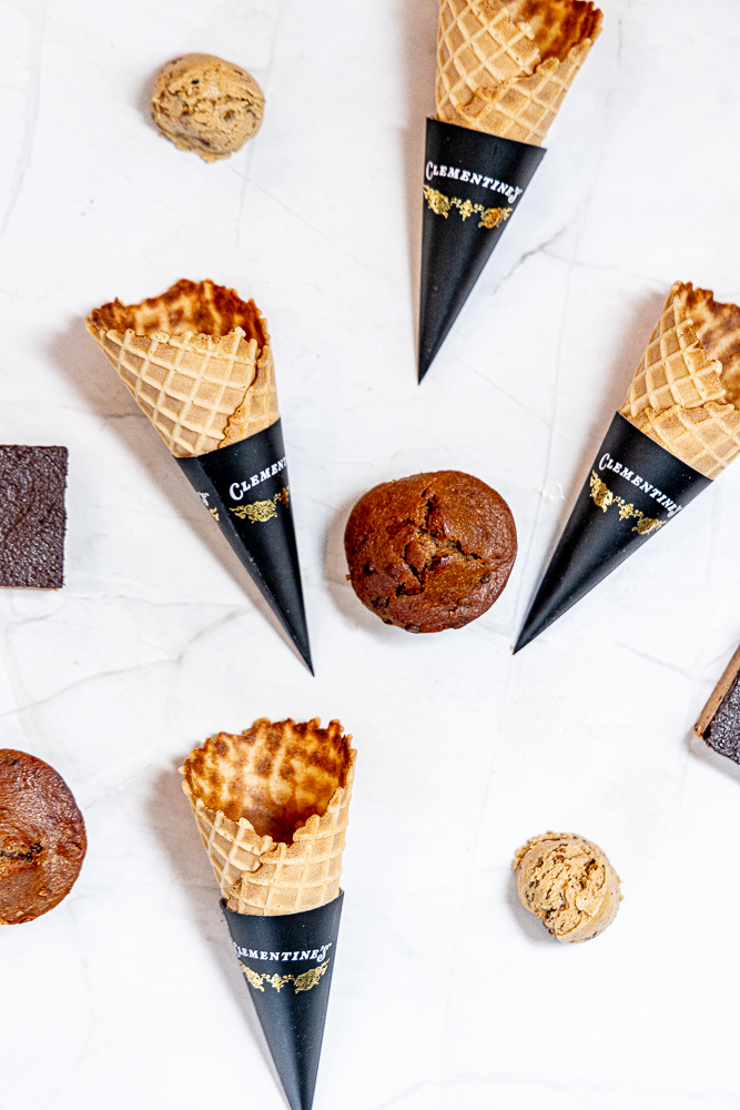 Ice cream cones, cookies, and chocolate pieces on a white surface.