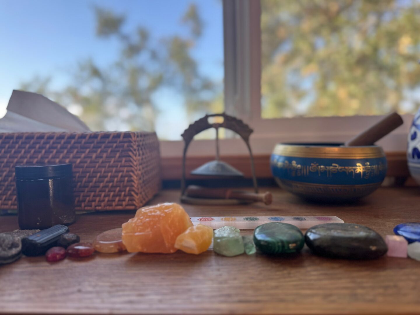 Wooden surface with a basket, stones, and a bowl near a window with trees outside.